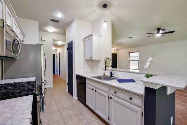 1119 Brinkley Dr, Cedar Park, TX 78613 - kitchen featuring black dishwasher, stainless steel microwave, a peninsula, gas range oven, and a ceiling fan