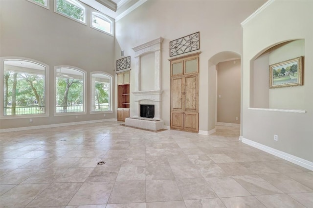 25 Meadows End Dr, Georgetown, TX 78628 - unfurnished living room featuring a high ceiling, plenty of natural light, a fireplace with raised hearth, crown molding, and arched walkways