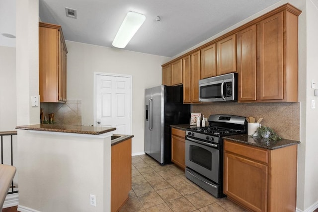 14815 Avery Ranch Blvd Unit 3301, Austin, TX 78717 - kitchen featuring stainless steel appliances, a peninsula, tasteful backsplash, and brown cabinets