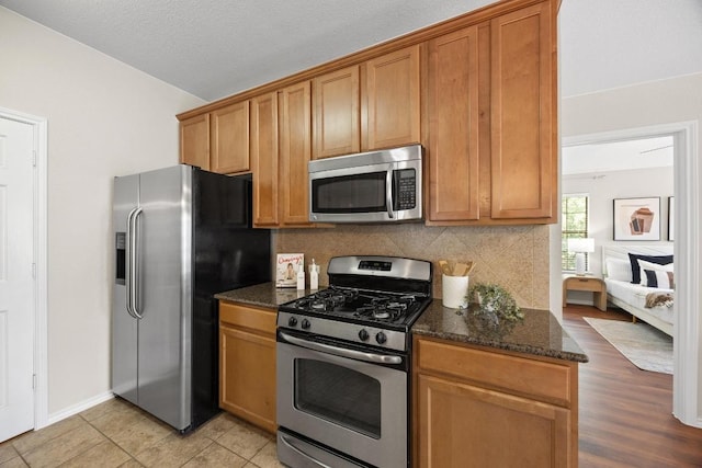 14815 Avery Ranch Blvd Unit 3301, Austin, TX 78717 - kitchen featuring stainless steel appliances, tasteful backsplash, dark stone countertops, brown cabinetry, and vaulted ceiling