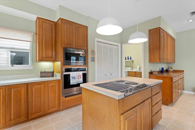 124 Hurst Creek Rd, Austin, TX 78734 - kitchen featuring appliances with stainless steel finishes, separate washer and dryer, light tile patterned floors, decorative light fixtures, and brown cabinetry
