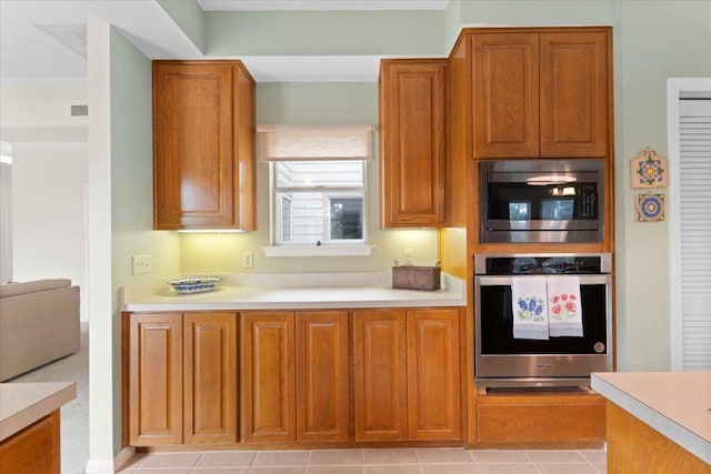 124 Hurst Creek Rd, Austin, TX 78734 - kitchen featuring appliances with stainless steel finishes, light countertops, brown cabinets, light tile patterned floors, and ornamental molding
