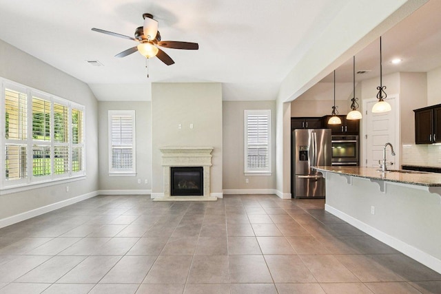 3213 Venezia Vw, Leander, TX 78641 - unfurnished living room with a ceiling fan, a glass covered fireplace, and light tile patterned floors