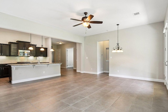 3213 Venezia Vw, Leander, TX 78641 - kitchen with stainless steel microwave, a ceiling fan, backsplash, a breakfast bar area, and light tile patterned flooring
