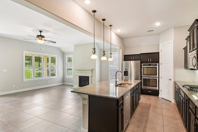 3213 Venezia Vw, Leander, TX 78641 - kitchen with appliances with stainless steel finishes, open floor plan, decorative backsplash, ceiling fan, and a glass covered fireplace