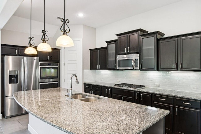 3213 Venezia Vw, Leander, TX 78641 - kitchen featuring stainless steel appliances, decorative backsplash, a center island with sink, light tile patterned floors, and light stone counters