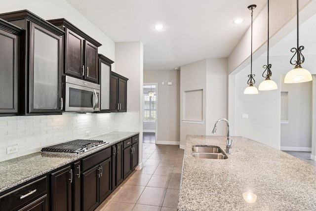 3213 Venezia Vw, Leander, TX 78641 - kitchen featuring appliances with stainless steel finishes, backsplash, light stone counters, light tile patterned flooring, and decorative light fixtures