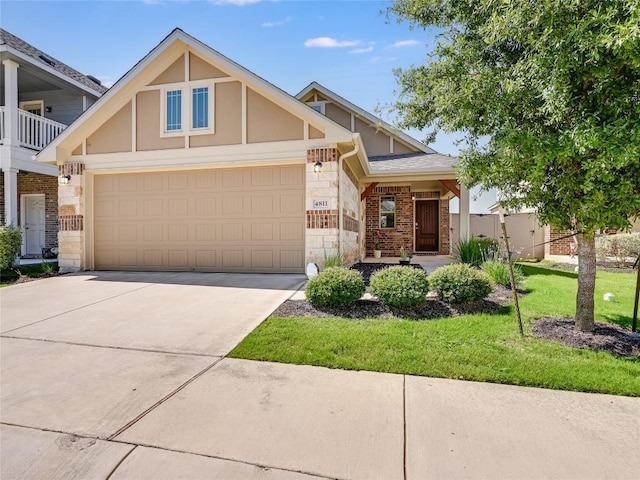 4811 Portillo Way, Pflugerville, TX 78660 - view of front of property featuring driveway, stone siding, a front lawn, brick siding, and a garage