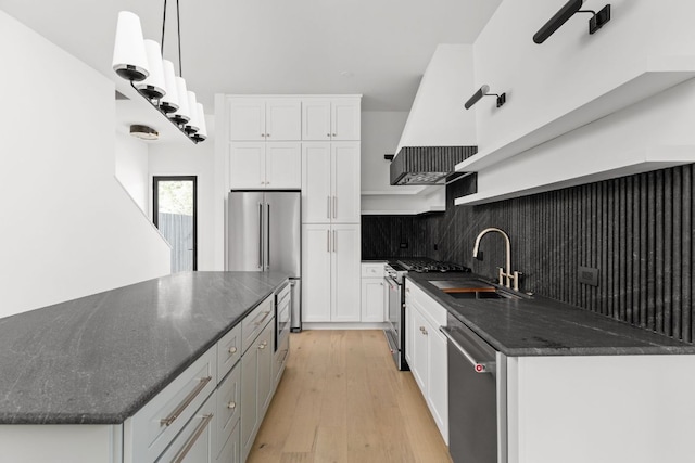 501 E 50th St, Austin, TX 78751 - kitchen with stainless steel appliances, white cabinetry, light wood-style floors, dark stone counters, and exhaust hood