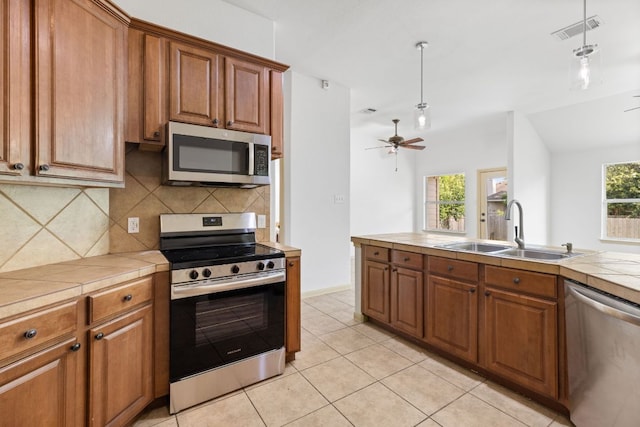 325 Swenson Dr, Hutto, TX 78634 - kitchen featuring appliances with stainless steel finishes, tile counters, and brown cabinets