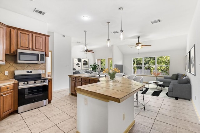 325 Swenson Dr, Hutto, TX 78634 - kitchen with stainless steel appliances, open floor plan, a ceiling fan, light tile patterned floors, and tasteful backsplash