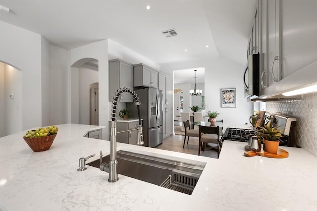 4608 Hibiscus Valley Dr, Austin, TX 78739 - kitchen with arched walkways, appliances with stainless steel finishes, gray cabinets, light stone counters, and recessed lighting
