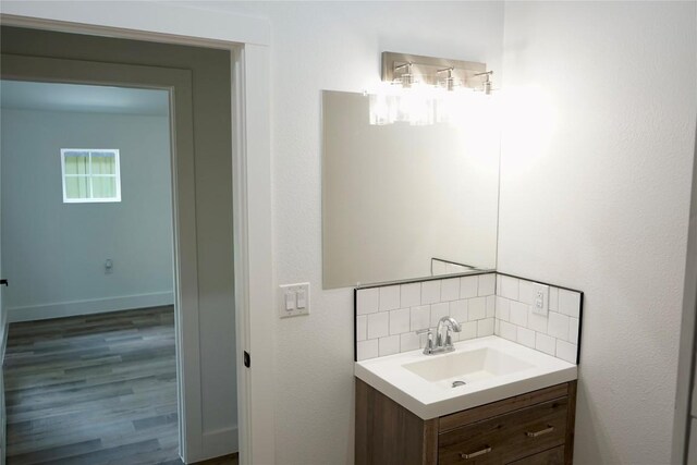 545 W Vaughan St, Bertram, TX 78605 - bathroom with vanity, tasteful backsplash, and wood finished floors