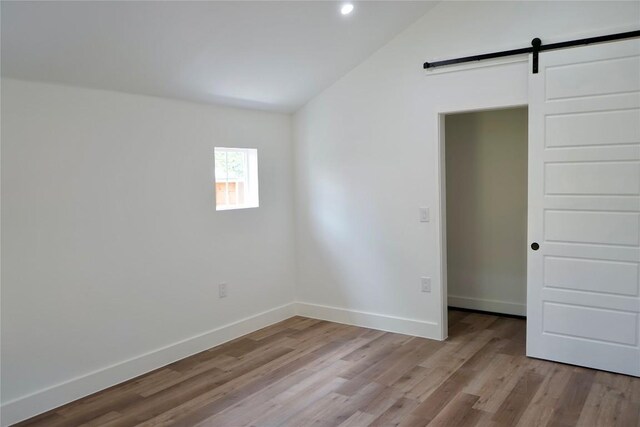 545 W Vaughan St, Bertram, TX 78605 - unfurnished room with vaulted ceiling, wood finished floors, a barn door, and recessed lighting