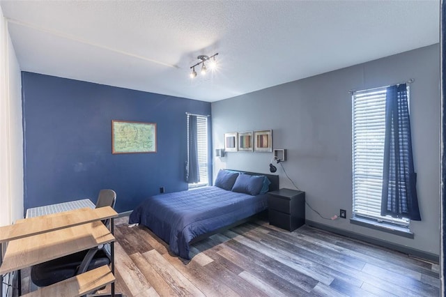 3431 N Hills Dr Unit 115, Austin, TX 78731 - bedroom featuring wood finished floors, multiple windows, and a textured ceiling
