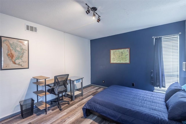 3431 N Hills Dr Unit 115, Austin, TX 78731 - bedroom featuring wood finished floors, track lighting, a textured ceiling, and an office area