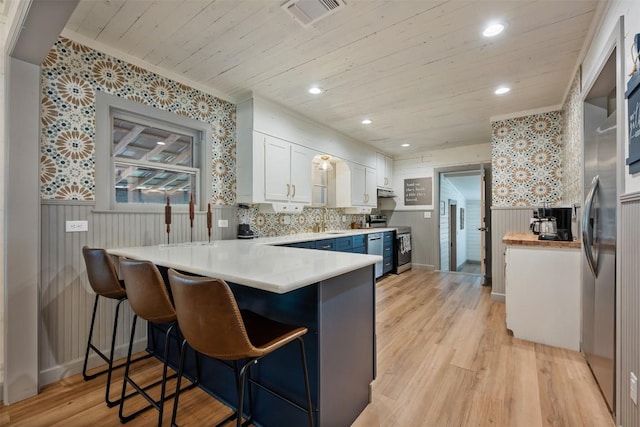 1211 S Church St, Georgetown, TX 78626 - kitchen featuring a peninsula, wooden ceiling, a wainscoted wall, white cabinets, and light wood-type flooring