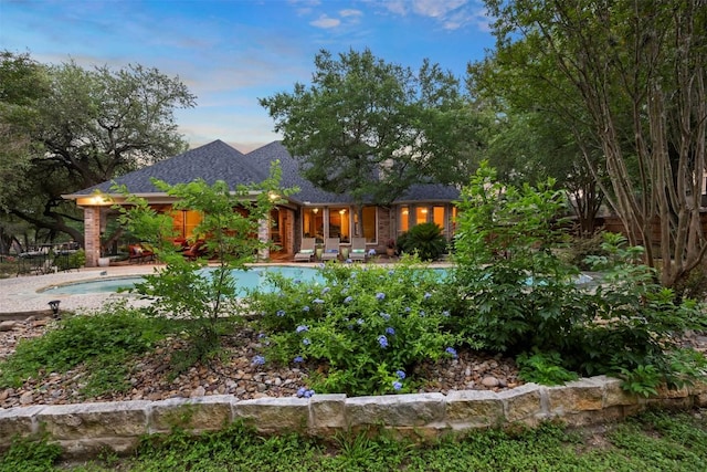 9920 Michelle Hl, Garden Ridge, TX 78266 - back of house at dusk featuring an outdoor pool, a patio area, and roof with shingles