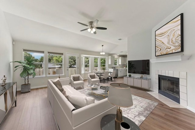 906 Jasmine Trl, Georgetown, TX 78626 - living room with lofted ceiling, light wood-type flooring, a ceiling fan, and a tile fireplace