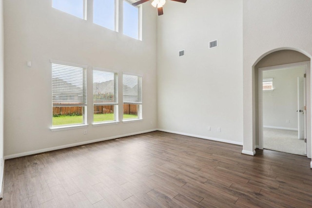 20025 Rhiannon Ln, Pflugerville, TX 78660 - empty room with arched walkways, a towering ceiling, a ceiling fan, healthy amount of natural light, and dark wood-style flooring