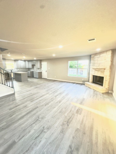 1237 Pelican Pl, New Braunfels, TX 78130 - unfurnished living room with wood finished floors, a stone fireplace, recessed lighting, and stairs