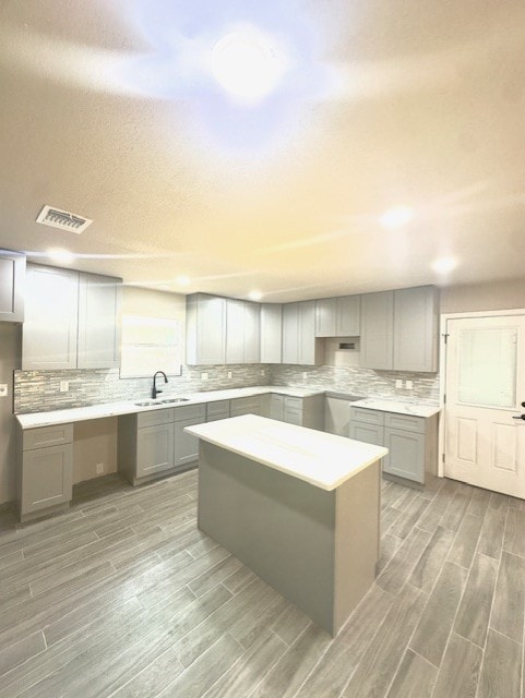 1237 Pelican Pl, New Braunfels, TX 78130 - kitchen with gray cabinets, light wood-style floors, tasteful backsplash, a kitchen island, and recessed lighting