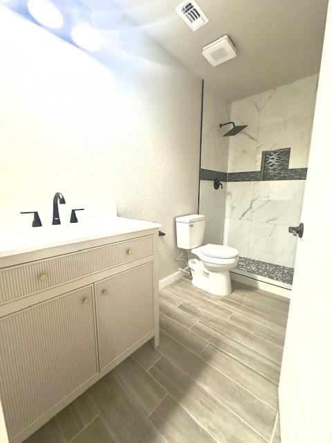 1237 Pelican Pl, New Braunfels, TX 78130 - bathroom featuring a tile shower, wood finish floors, and vanity