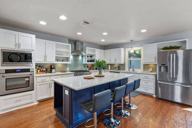 611 W Johanna St, Austin, TX 78704 - kitchen featuring stainless steel appliances, wall chimney range hood, open shelves, a breakfast bar area, and white cabinets
