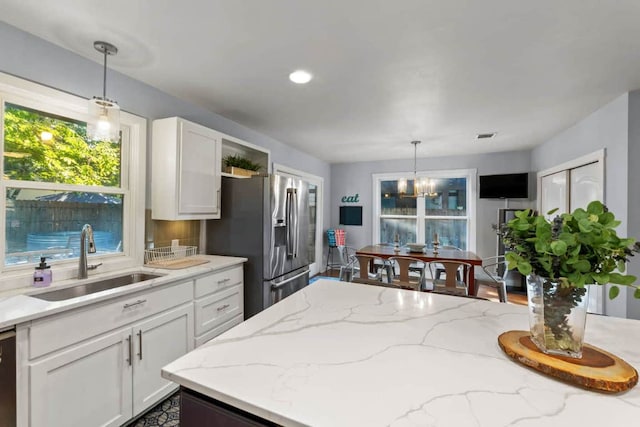 611 W Johanna St, Austin, TX 78704 - kitchen featuring stainless steel refrigerator with ice dispenser, white cabinets, a chandelier, pendant lighting, and light stone countertops