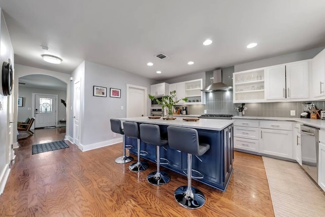 611 W Johanna St, Austin, TX 78704 - kitchen with wall chimney range hood, open shelves, arched walkways, stainless steel appliances, and light wood-style floors