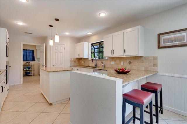 9410 Topridge Dr, Austin, TX 78750 - kitchen featuring a peninsula, white cabinetry, oven, tasteful backsplash, and wainscoting