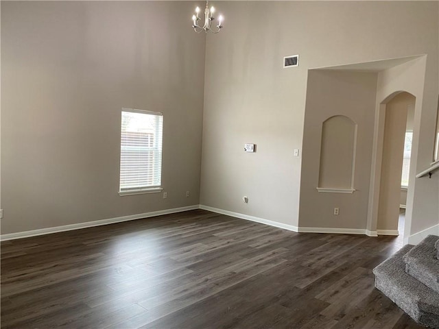 2700 Saddle Blanket Pl, Leander, TX 78641 - spare room featuring stairs, a high ceiling, dark wood finished floors, a chandelier, and arched walkways