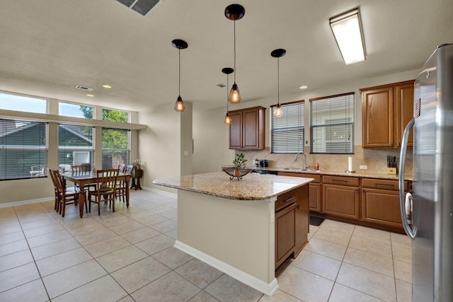 201 Trestle Tree, San Marcos, TX 78666 - kitchen featuring freestanding refrigerator, light tile patterned floors, tasteful backsplash, brown cabinets, and recessed lighting