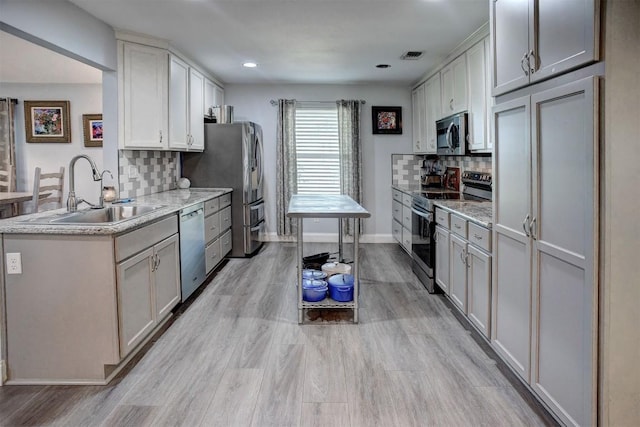 569 Mcallister Rd, Bastrop, TX 78602 - kitchen featuring stainless steel appliances, backsplash, light wood finished floors, recessed lighting, and light stone counters