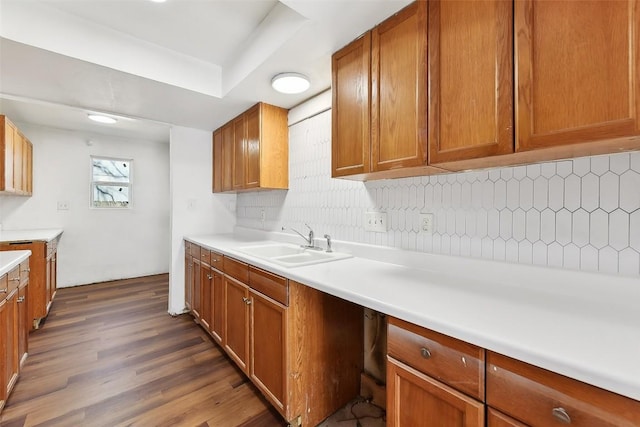3810 Leafield Dr, Austin, TX 78749 - kitchen featuring tasteful backsplash, dark wood-style floors, brown cabinetry, light countertops, and a raised ceiling
