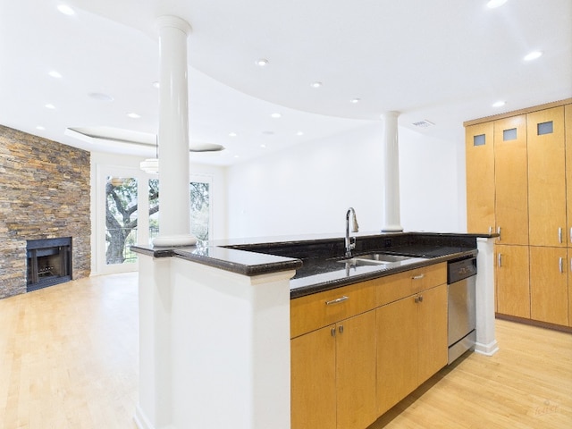 1501 Barton Springs Rd Unit 222, Austin, TX 78704 - kitchen with stainless steel dishwasher, light wood-style floors, dark stone countertops, a fireplace, and recessed lighting