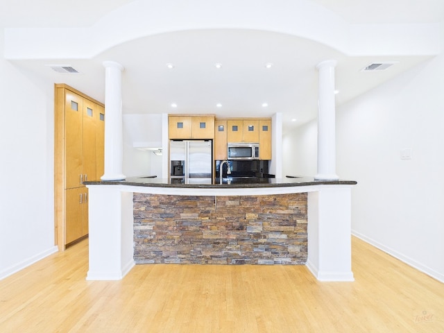 1501 Barton Springs Rd Unit 222, Austin, TX 78704 - kitchen with appliances with stainless steel finishes, ornate columns, light wood-style floors, recessed lighting, and dark stone countertops