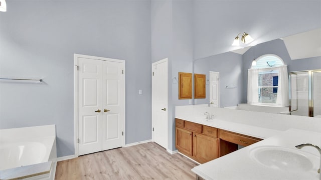 606 Dundalk Bay Cv, Pflugerville, TX 78660 - bathroom featuring double vanity, wood finished floors, a bath, a stall shower, and high vaulted ceiling