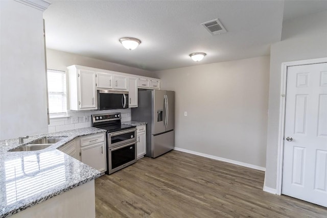 706 Brown St, Lampasas, TX 76550 - kitchen with stainless steel appliances, wood finished floors, light stone counters, and white cabinetry