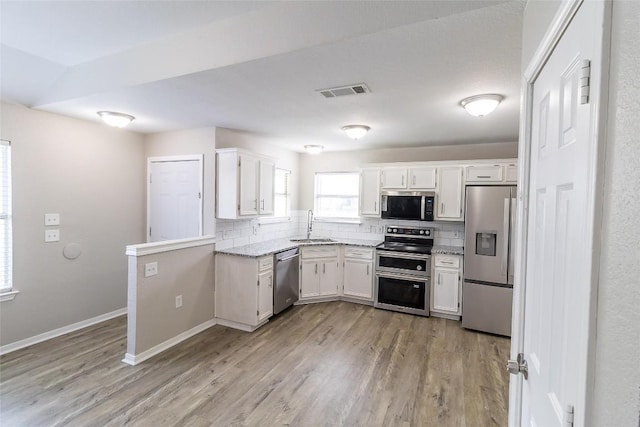706 Brown St, Lampasas, TX 76550 - kitchen featuring appliances with stainless steel finishes, white cabinetry, decorative backsplash, light wood finished floors, and light stone counters