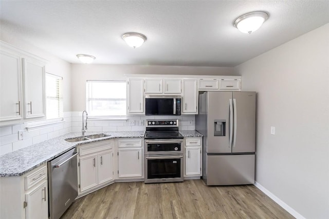 706 Brown St, Lampasas, TX 76550 - kitchen featuring appliances with stainless steel finishes, white cabinetry, decorative backsplash, and light wood-type flooring