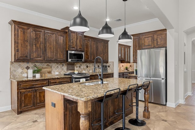 100 Crystal Cv, Round Rock, TX 78664 - kitchen featuring appliances with stainless steel finishes, light stone countertops, dark brown cabinets, pendant lighting, and a center island with sink