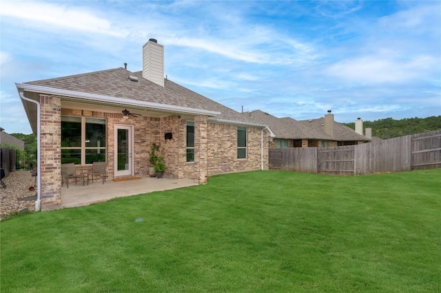 5612 Wild Foxglove Rd, Spicewood, TX 78669 - back of property with a fenced backyard, brick siding, and a patio area