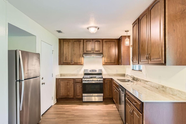 2112 Cindy Ln, Austin, TX 78727 - kitchen with appliances with stainless steel finishes, light wood-style flooring, under cabinet range hood, light countertops, and brown cabinetry
