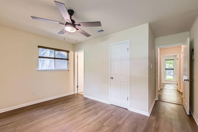 2112 Cindy Ln, Austin, TX 78727 - unfurnished bedroom featuring wood finished floors, multiple windows, a textured ceiling, and ceiling fan
