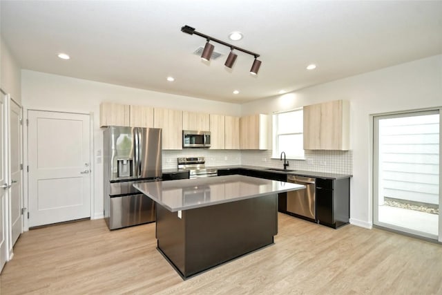 7601 Cooper Ln Unit 25, Austin, TX 78745 - kitchen with appliances with stainless steel finishes, light brown cabinetry, a center island, light wood-style flooring, and recessed lighting