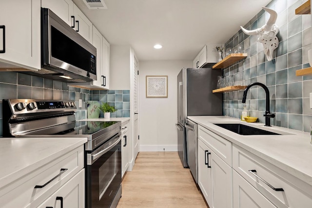 1206 Hollow Creek Dr Unit 3, Austin, TX 78704 - kitchen with appliances with stainless steel finishes, backsplash, light countertops, white cabinets, and recessed lighting
