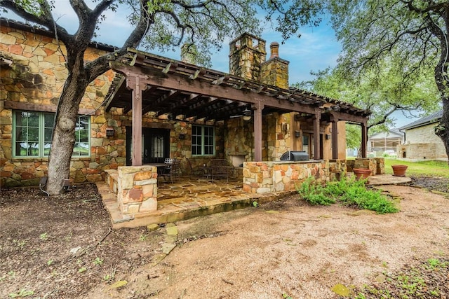 171 Oak Grove Cv, Georgetown, TX 78628 - back of house with stone siding, a chimney, area for grilling, and a patio area
