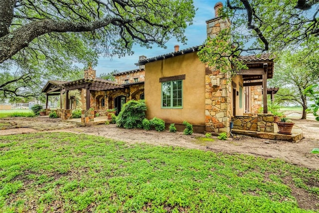171 Oak Grove Cv, Georgetown, TX 78628 - view of front of home with a chimney, stone siding, stucco siding, and a pergola