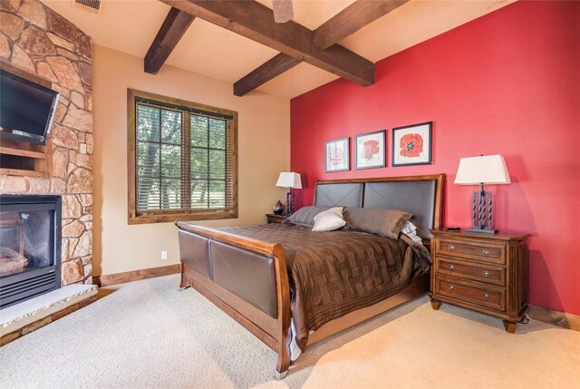 171 Oak Grove Cv, Georgetown, TX 78628 - bedroom featuring carpet flooring, beamed ceiling, and a stone fireplace